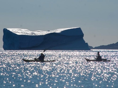 Paddling boats near spectacular iceberg.