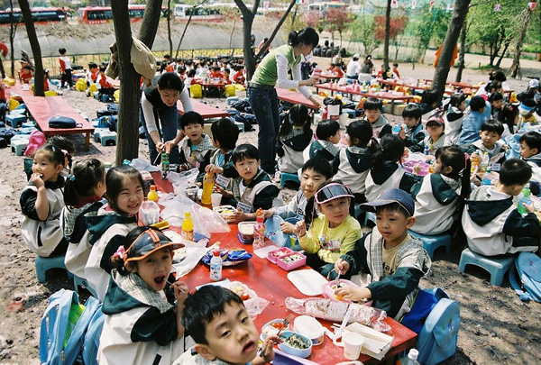 Ansan, Korea with children sharing meal served by volunteers.