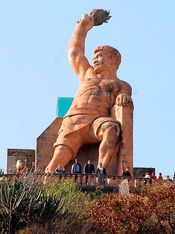 Statue of Pípila with torch, towering over the city