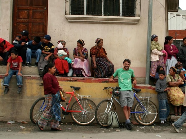 Author with bike watching a parade as an independent traveler in Guatemala.