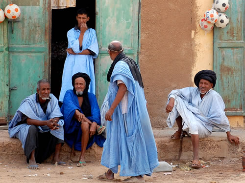 Men in robes gathering outside a shop.