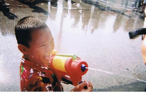 Songkran festival with child spraying water.