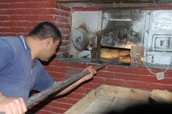 Baker taking Khobbz bread from the oven.