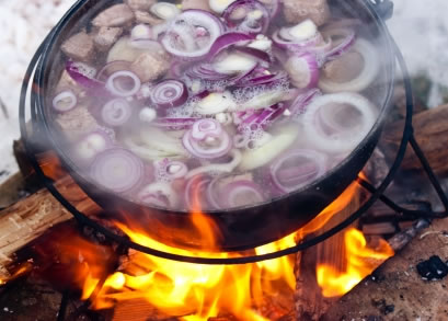 A soup cooking on a wood fire is one example of the author's food adventures abroad.