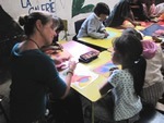 Woman traveler on a teaching job with children at a desk in Guatemala thumbnail.