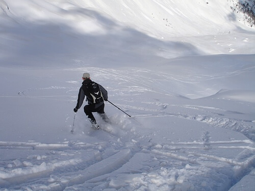 Man working a job in ski instruction scoping out a slope after a new snow.