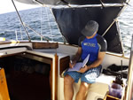 Man working on a virtual job sitting on boat with laptop thumbnail.