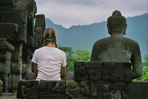 Sitting next to Buddha statue.