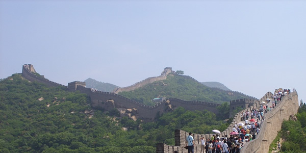 The great wall of China with many tourists crossing far through the rolling hills.