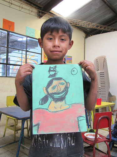 Art class in Guatemala with boy holding his drawing.